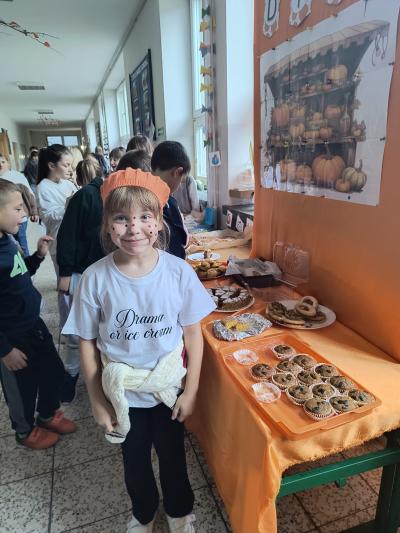 Dziecko przebrane za dynię i stoisko z ciasteczkami z dyni.