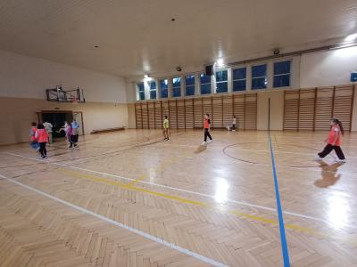 Uczniowie grają w piłkę na hali sportowej.