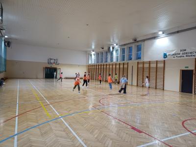 Uczniowie grają w piłkę na hali sportowej.
