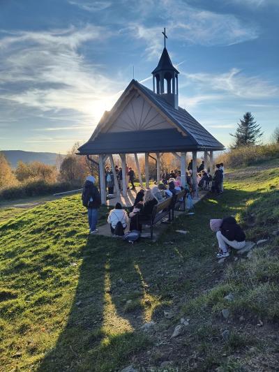 Uczniowie siedzą koło ołtarza polowego na Potaczkowej Górze.