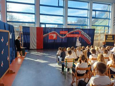 Uczennica w białej sukience tańczy na scenie.