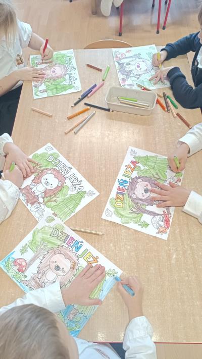 Dzieci kolorują kolorowankę z jeżem.