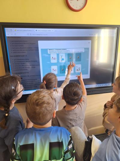 Uczniowie grają w grę edukacyjną na tablicy multimedialnej.