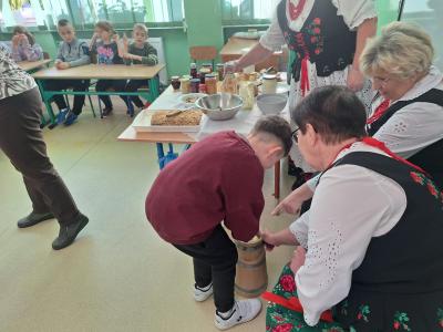 Uczeń robi masło w maślniczce.