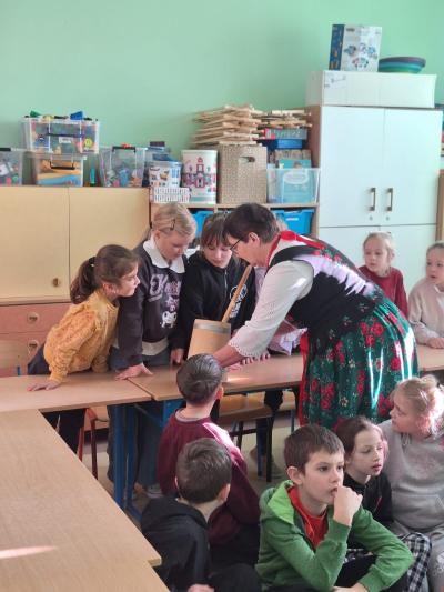 Pani z Koła Gospodyń Wiejskich pokazuje dzieciom zrobione masło.