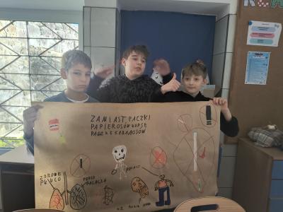Uczniowie prezentują wykonany przez siebie plakat  na temat rzucania palenia papierosów.
