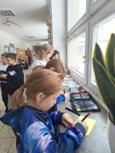 Uczniowie rozwiązują łamigłówki na parapecie szkolnym.