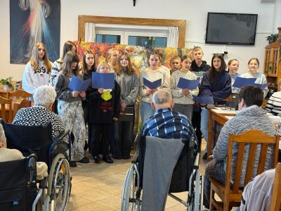 Uczniowie śpiewają pieśń, a osoby chore i starsze słuchają.