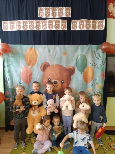 Dzieci stoją w grupie i trzymają w dłoniach maskotki.