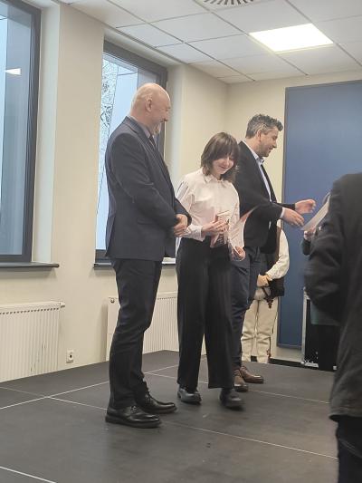 Uczennica trzyma w dłoniach dyplom i pozuje wraz z jury do zdjęcia.