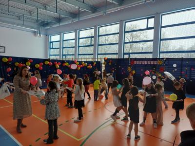 Uczniowie odbijają w parach balon w rytm muzyki, przy użyciu kartki gazety.