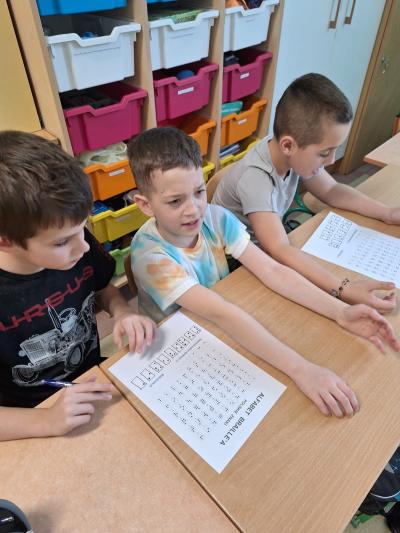 Uczniowie czytają brajlem na kartce.