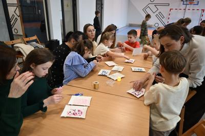 Rodzice wraz z dziećmi wykonują gwiazdki z koralików.