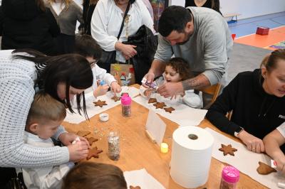 Rodzice wraz z dziećmi ozdabiają pierniczki.