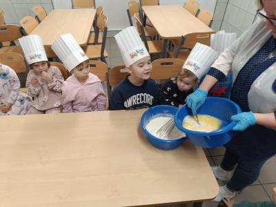 Przedszkolaki oglądają jak kucharka robi ciasto.
