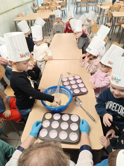 Dziecko nalewa ciasto do foremki.