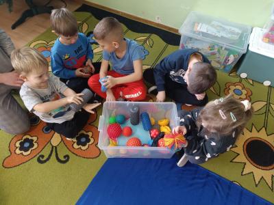Dzieci pracują z pomocami sensorycznymi - wałki, kule, piłki.