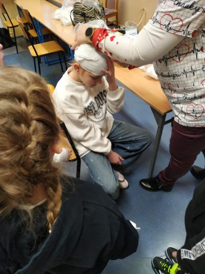 Pielęgniarka demonstruje, jak zabandażować głowę.