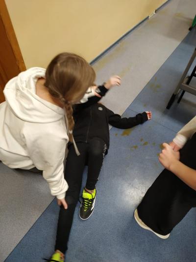 Uczennica ćwiczy pozycję bezpieczną na swojej koleżance.