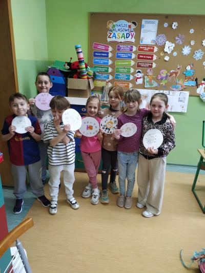 Uczniowie klasy pierwszej trzymają w dłoniach tarcze prywatności.