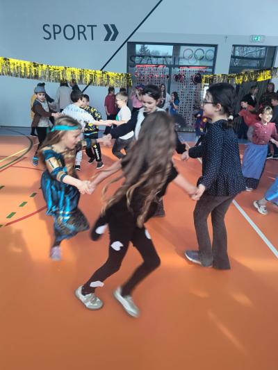 Uczniowie tańczą na sali gimnastycznej.