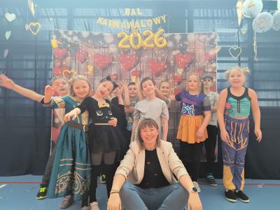 Uczniowie pozują do zdjęcia na tle walentynkowym- w serduszka.