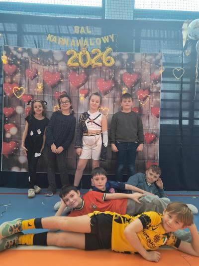 Uczniowie pozują do zdjęcia na tle walentynkowym- w serduszka.