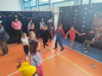 Uczniowie tańczą na sali gimnastycznej.