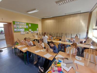 Uczniowie malują farbami akrylowymi na płótnach i sztalugach.