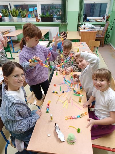 Uczniowie sklejają łańcuch na choinkę.