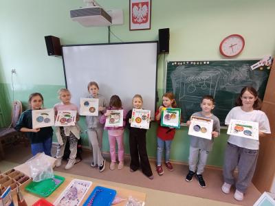 Uczniowie trzymają w rękach świąteczne obrazy.
