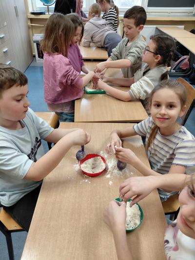 Uczniowie robią gniotki z balonów i mąki.