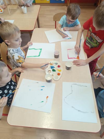 Dzieci malują farbami na płótnie.