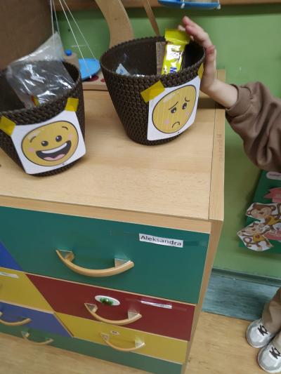 Dziecko wkłada opakowanie po przekąsce do smutnego koszyka.