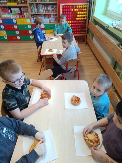 Dzieci zjadają zrobione przez siebie pizzy.