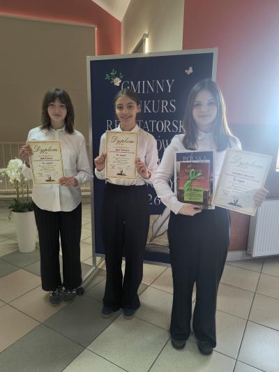 Uczennice trzymają w dłoniach dyplomy i nagrody.