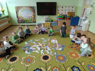Dzieci siedzą w kole na dywanie, a w środku znajdują się wykonane przez  ich kolorowe skarpetki.