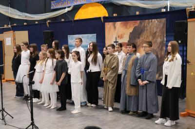 Uczniowie stoją w grupie i śpiewają pieśń.