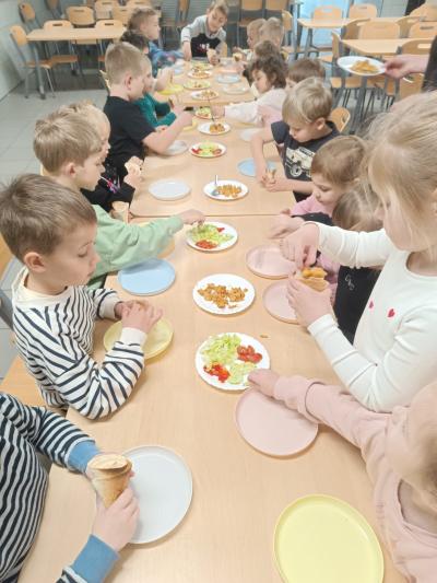 Dzieci robią tortille z warzywami i kurczakiem.