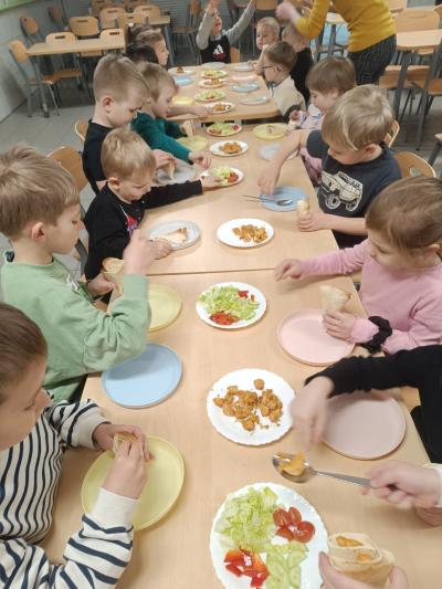 Dzieci robią tortille z warzywami i kurczakiem.
