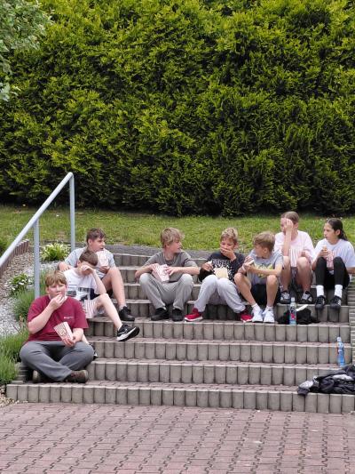 Uczniowie jedzą pop corn na schodach.