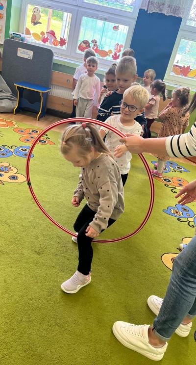 Dzieci przechodzą przez hula-hop.