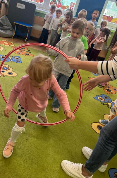 Dzieci przechodzą przez hula-hop.