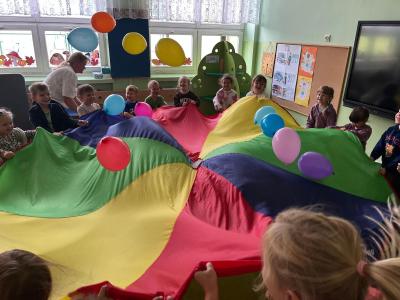 Dzieci odbijają bawią się balonami i chustą animacyjną.